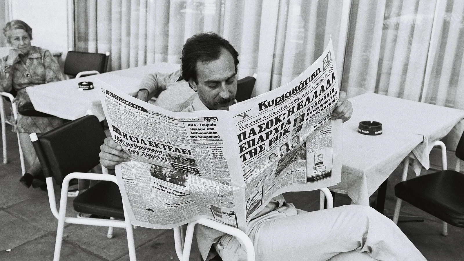 Man reading a newspaper at a café terrace in Athens, Greece   1979