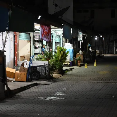 DFC 1772 Dimly lit row of closed storefronts and market stalls along a quiet empty street at night